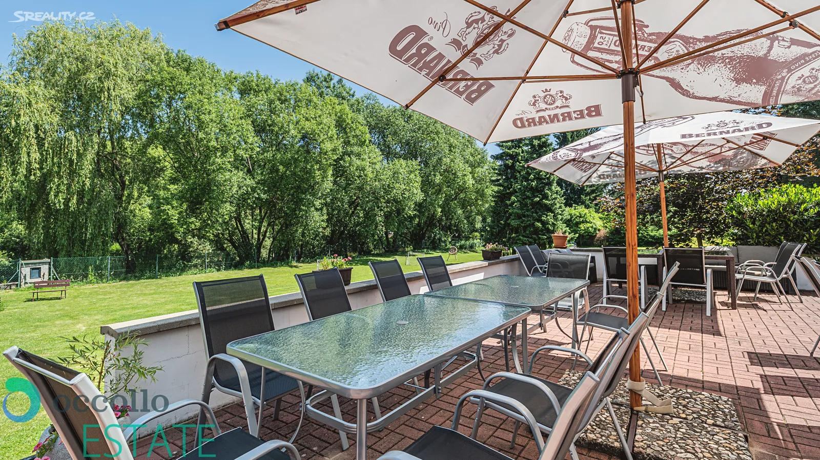 The garden terrace with long tables and parasols behind the accommodation