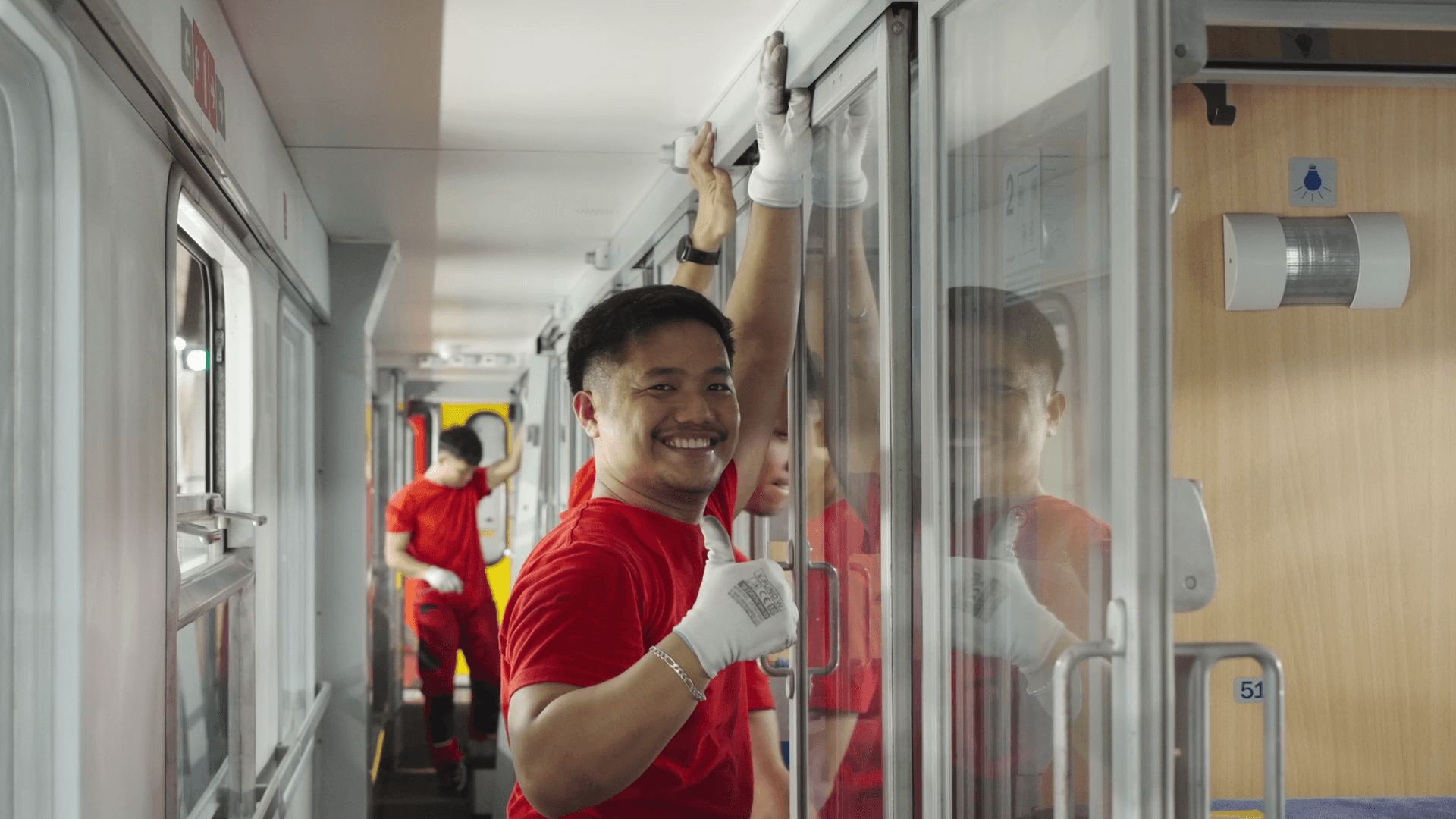 A colleague cleaning the glass doors inside a carriage