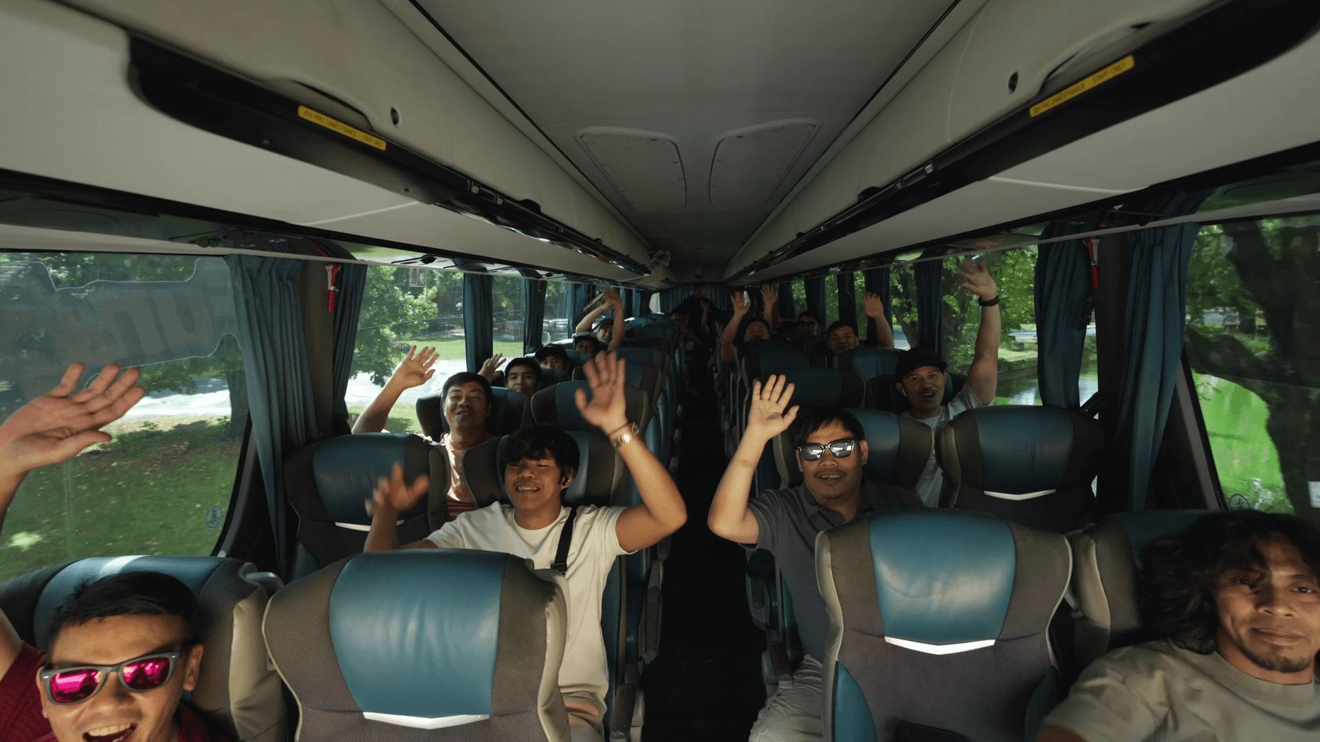 Colleagues waving from their seats inside the coach on the way to a trip